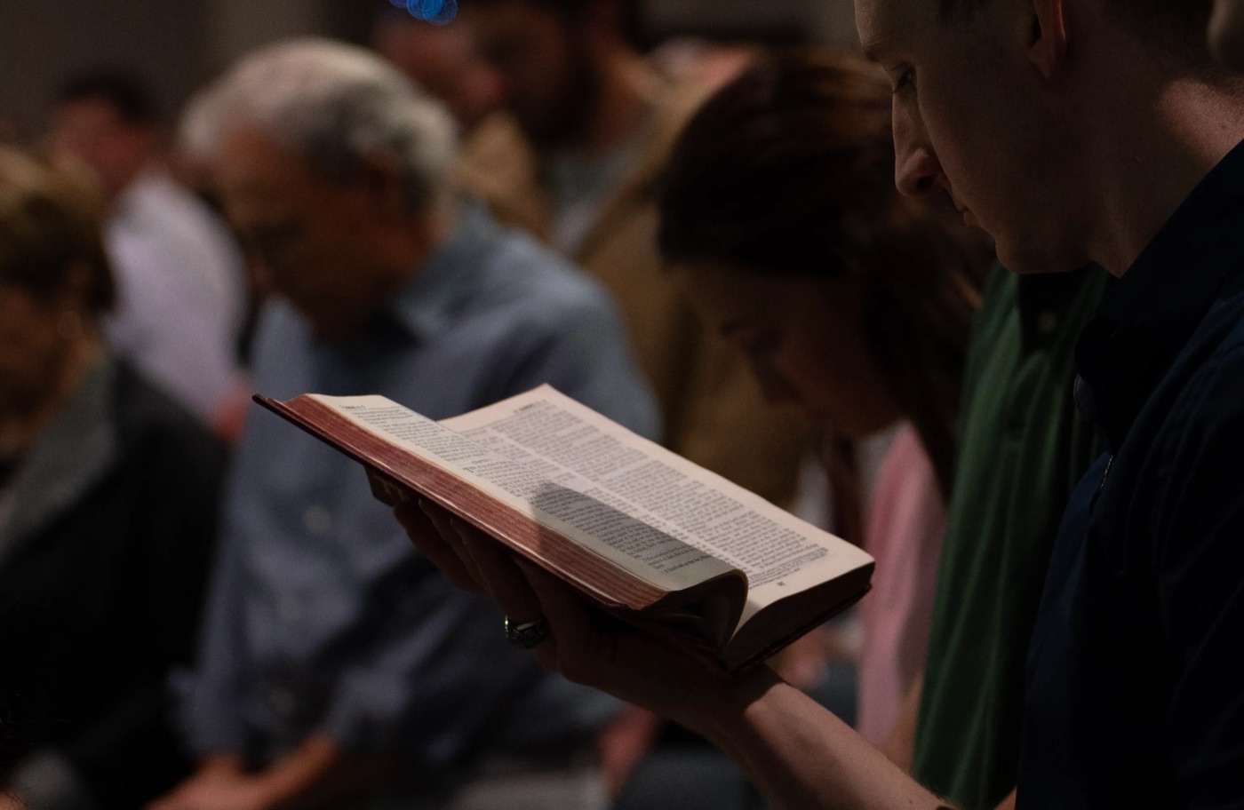 A congregation member reading scripture during worship